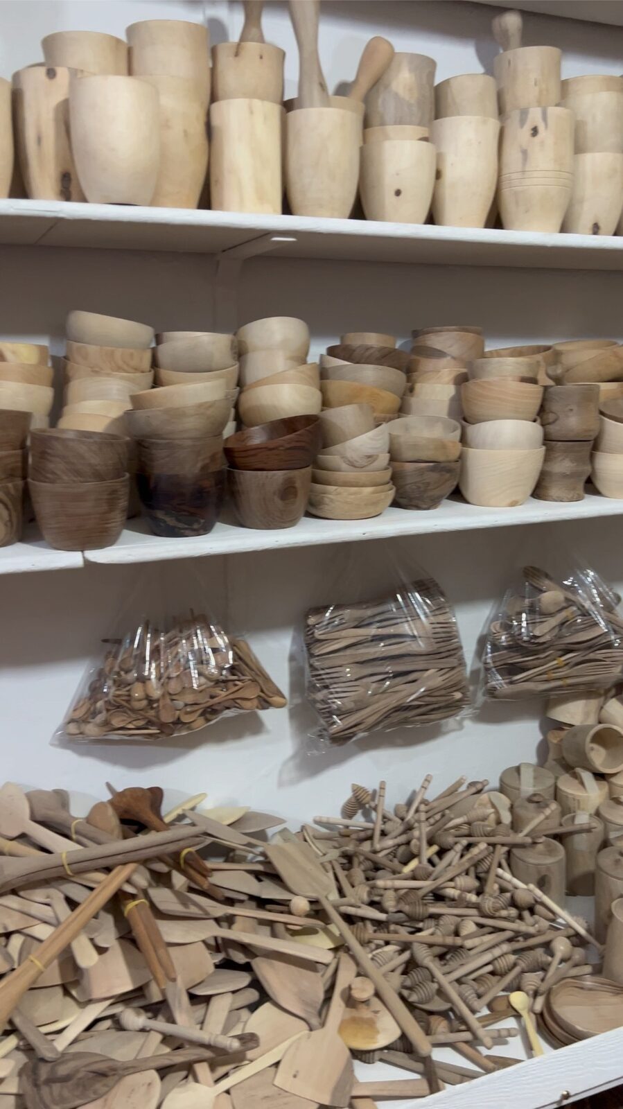 Stacked hand-carved Moroccan wooden bowls and serving pieces in a Marrakech workshop.
